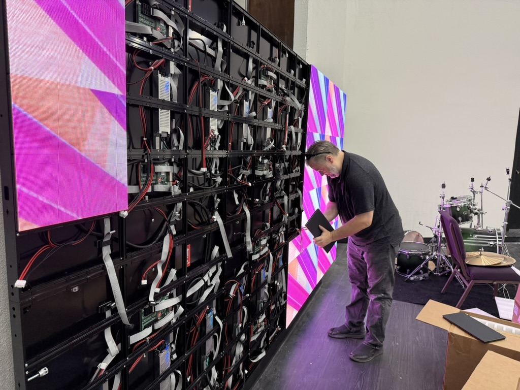 A technician working behind a large LED video wall